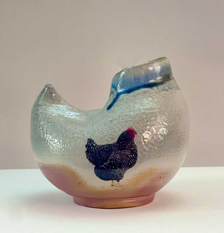 Chicken-shaped vase with image of rooster on it.